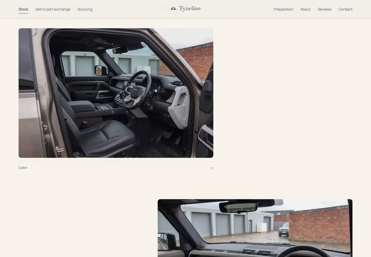 The right-hand-drive cabin of a Land Rover Defender 110, photographed through the open driver's door on a UK forecourt